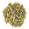 A pile of whole green cardamom pods is arranged in a loose circle on a white background, highlighting their vibrant green color and aromatic presence. Product type: whole cardamom pods. Color: medium to light green, subtle natural variation. Surface finish: matte with faint ridges visible on shells. Shape: oval, slightly elongated pods with pointed tips. Background is solid white; no packaging or labels present. No people or hands in the image; top-down view shows clear separation between pods and clean