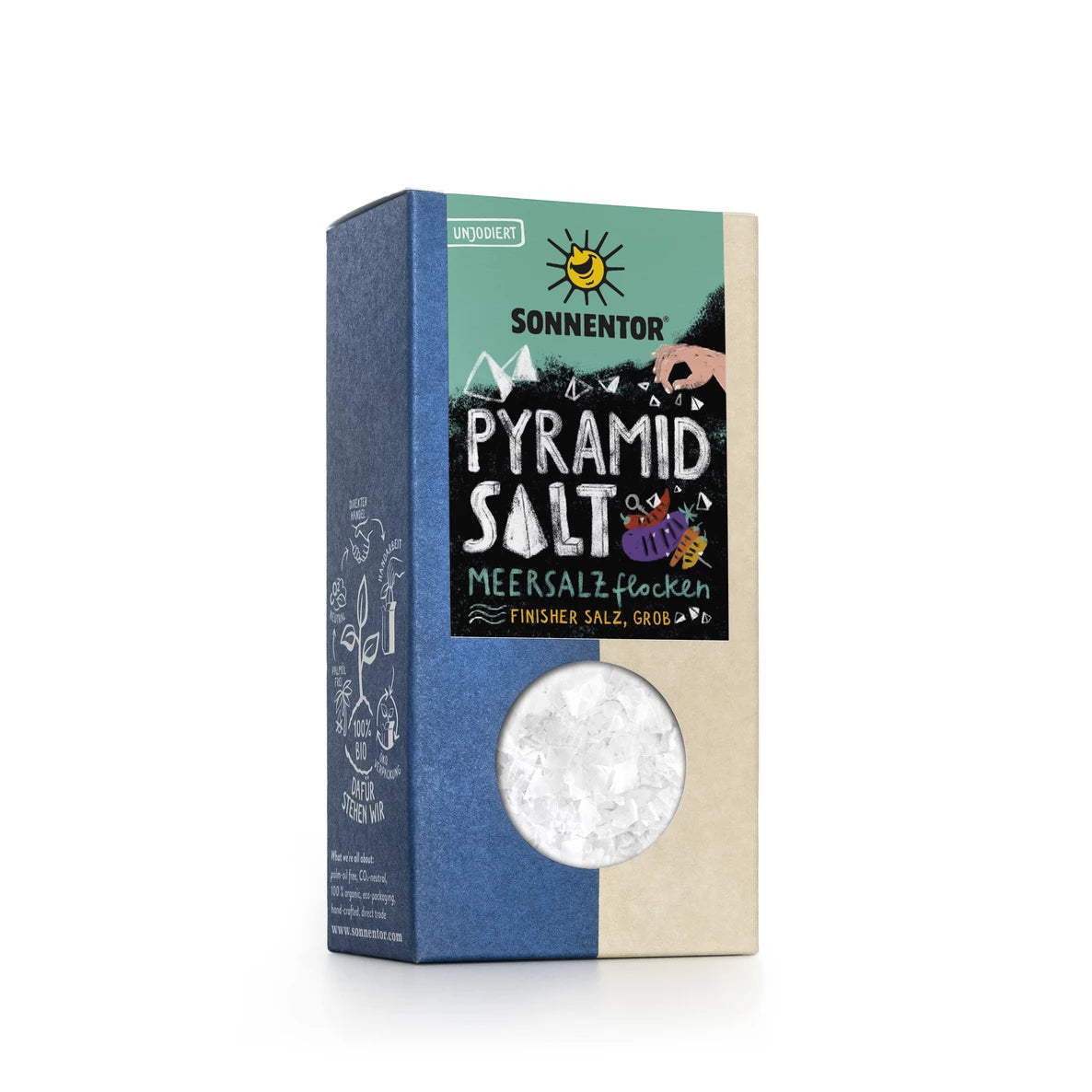 Laatikko Sonnentor Pyramid Salt -tuotetta, jossa on värikkäitä kuvituksia, kirkas ikkuna näyttämässä suuria merisuolahiutaleita ja saksankielinen teksti, joka kuvaa tuotetta pyramidinmuotoisiksi Meersalzflocken-hiutaleiksi. Laatikko on suorakulmainen mattapinnalla, ja siinä on pääteviivatonta typografiaa. Tausta on pelkistetty ja siisti. Ihmisiä tai käsiä ei näy kuvassa.