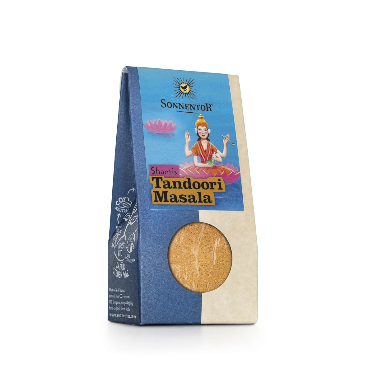 Sininen ja beige pakkaus Sonnentor Shantis Tandoori Masala -mausteseosta, jossa on kuvitus soittimen soittajanaisesta ja pyöreä ikkuna näyttämässä eloisa tandoori masala sisällä. Suorakulmainen laatikko on mattapintainen, pääteviivattomalla ja antiikva-etikettitekstillä. Sonnentor näkyy yläosassa. Tuote on kuvattu pelkistettyä valkoista taustaa vasten suoraviivaisessa tuotekuvassa. Ihmisiä tai käsiä ei näy.