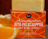 Sopo Aurinkoinen Aito Palasaippua; oranssinvärinen saippuapala lepää oranssilla laatikolla tekstillä "Aito Palasaippua"; saippua suorakulmainen sileine reunoineen ja mattapinnalla; laatikossa lihavoituja valkoisia ja oransseja geometrisia kuvioita sekä suuria groteskifontteja; kuvan alaosassa epätarkkoja appelsiiniviipaleita; ei ihmisiä eikä käsiä näkyvissä, lähikuva tuotteesta.