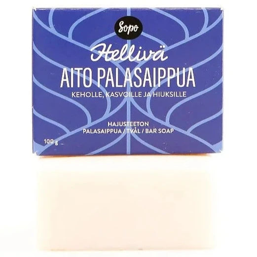 Sopo Hellivä Aito Palasaippua Hajusteeton; suorakulmainen valkoinen saippuapala mattapinnalla sijoitettuna sinisen suorakaiteen muotoisen pahvilaatikon alle; laatikossa groteskityyppinen teksti "Sopo Hellivä Aito Palasaippua" etusivulla ja pienempää lisätekstiä; ei ihmisiä eikä käsiä näkyvissä; tausta puhtaan valkoinen, kuva otettu hieman koholta edestä.