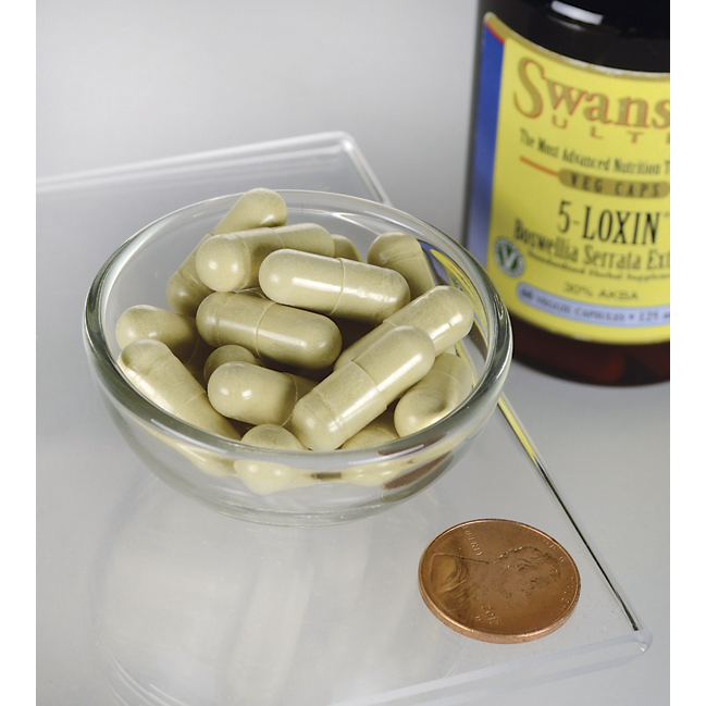 Swanson Boswellia Serrata Extract; pieni lasikulho täynnä vihertäviä kapseleita, kolikko vierellä kokoluokan osoittamiseksi, taustalla valkoinen muovipullo tekstillä Swanson 5-LOXIN ja Boswellia-uute; pullossa tummanvihreää tekstiä valkoisella etiketillä, osittain rajattu kuvan ulkopuolelle; ei ihmisiä tai käsiä; asetelma tasaisella neutraalilla pinnalla kuvattuna ylhäältä.