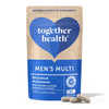 A blue and beige matte-finish pouch labeled “Mens Multi” from Together Health, with simple sans-serif white and dark text, stands upright. The package highlights wholefood multivitamins with plant-based ingredients. Two gray capsules are positioned in front of the pouch on a plain, light-colored surface. No people or hands are visible.