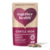 Together Health Gentle Iron Complex; mattapintainen pussi sydänkuvioin tekstillä "Gentle Iron Wholefood Supplement" pystyssä kolmen beigen kapselin vieressä; vaalea, suorakulmainen pussi saumattavalla yläosalla, yksinkertainen groteskiteksti; valkoinen tausta.