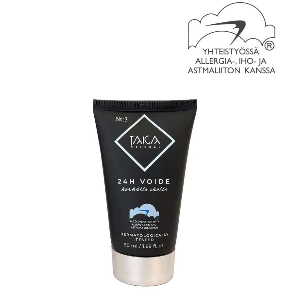 Taiga Cosmetics 24h Voide; musta tuubi merkitty "TAIGA NATURAL 24H VOIDE" pohjoismaisin tekstein, lähellä logoa pilvikuvion ja lisätekstin kera, joka osoittaa dermatologisen testauksen ja allergiayhteistyön; tuubi on sylinterinmuotoinen mattapinnalla ja valkoisella groteskitypografialla; asetelma on minimalistinen, ei ihmisiä tai käsiä näkyvissä; tausta yksivärinen; tuote korostaa luonnollisia ainesosia pitkäkestoiseen kosteutukseen.