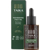 Taika Ravitseva Kasvoöljy; pullo ja pakkaus Taika Nourishing Face Oil -kasvoöljyä, merkitty kaikille ihotyypeille sopivaksi, 100 % vegaaniseksi ja luonnolliseksi; molemmat esineet raikkaan vihreitä valkoisin groteskitekstein; pakkauksessa hienovaraisia lehtikuvituksia; pinta mattapintainen; ei ihmisiä tai käsiä; kuvattu neutraalilla taustalla tavanomaisessa tuotekuvassa.