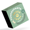 Vihreä rasia merkinnällä TUOKSUPANTA TASSU FOODS ja tassunjälkikuvituksella, sisältäen tuoksuvan koiranpannan kokoon 62 cm. Suorakulmaisessa pakkauksessa on suomenkielistä tietoa, musta koiran silhuettikuva ja mainita ainutlaatuisesta tuoksusta. Pinta on mattaa, ja teksti on lihavoitua pääteviivatonta fonttia. Ihmisiä tai käsiä ei näy, tausta on valkoinen.