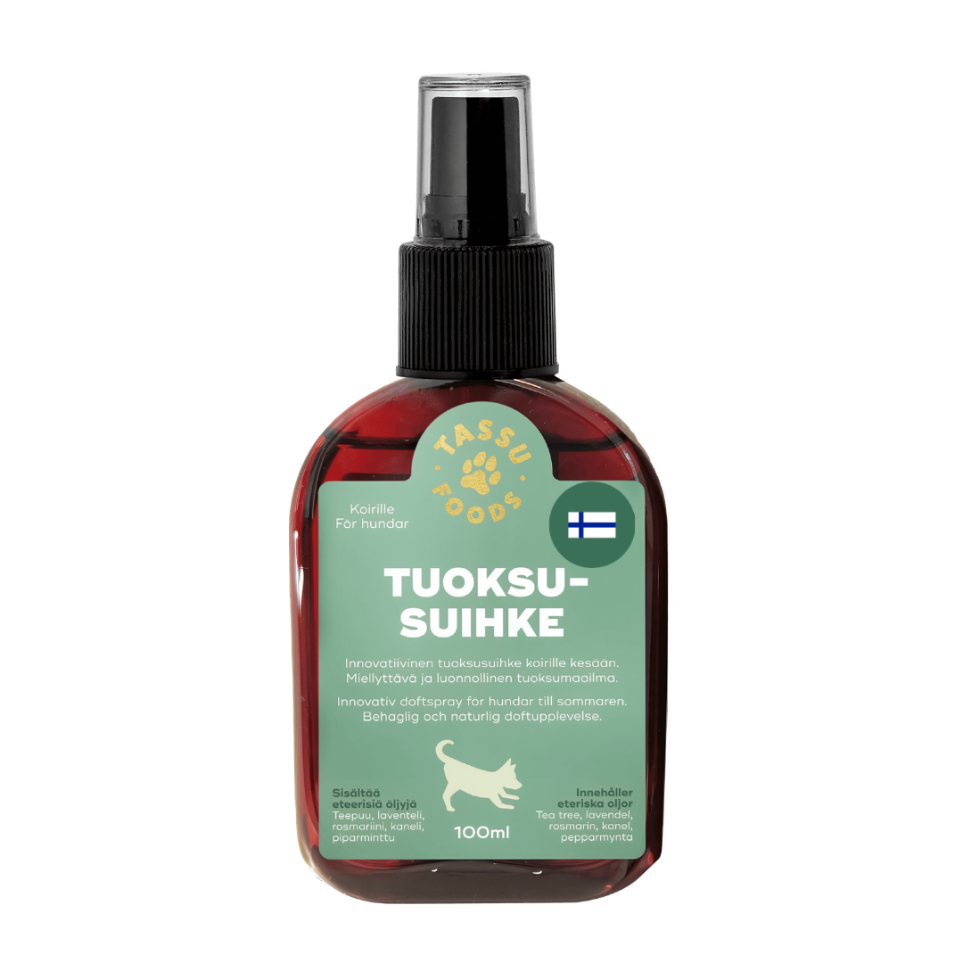 Tassu Foods Tuoksusuihke: punainen muovinen suihkepullo valkoisella liipaisinnokalla pystyasennossa; etiketti on mattapintainen, pääosin valkoinen sinisin ja punaisin korostuksin, teksti "Tuoksusuihke" näkyvästi groteskikirjasimella; etuosassa Suomen lippu ja yksinkertainen koiraikoni sekä pienempää suomenkielistä tekstiä; tilavuus "100ml" näkyy selvästi; valkoinen tausta, ei ihmisiä tai käsiä näkyvissä.