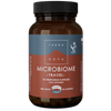 Terranova Microbiome Travel; ruskea lieriömäinen pullo mattapinnalla, merkitty ”Terra Nova Microbiome Travel”, sisältää 50 kasviskapselia; muovikorkki yksivärinen; etiketissä valkoista tikkukirjasintekstiä tummaa taustaa vasten, lihavoituja osioita ja useita fonttikokoja; näkyvissä väitteitä vegaanisuudesta, lisäaineettomuudesta ja matkakäytön tuesta; tausta tasainen ja neutraali, ei ihmisiä näkyvissä.
