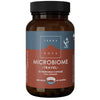 Terranova Microbiome Travel; ruskea lieriömäinen pullo mattapinnalla, merkitty ”Terra Nova Microbiome Travel”, sisältää 50 kasviskapselia; muovikorkki yksivärinen; etiketissä valkoista tikkukirjasintekstiä tummaa taustaa vasten, lihavoituja osioita ja useita fonttikokoja; näkyvissä väitteitä vegaanisuudesta, lisäaineettomuudesta ja matkakäytön tuesta; tausta tasainen ja neutraali, ei ihmisiä näkyvissä.