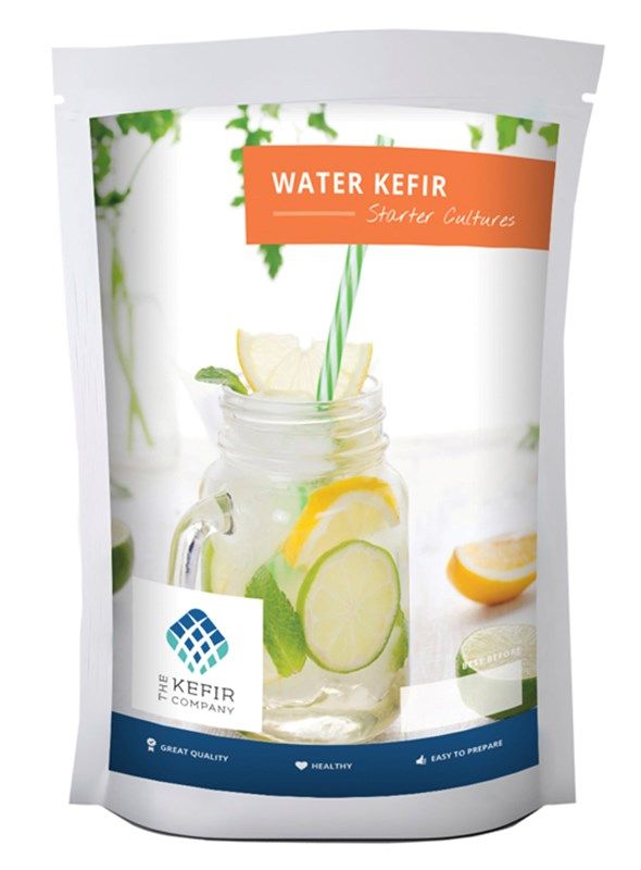 A packet of Water Kefir Starter Cultures, featuring an image of a mason jar filled with lemon, lime, mint, and a striped straw. Rectangular package with matte finish. Main colors are light blue and white. Clear branding from The Kefir Company is present at the top. Health icons appear in a row below the main image. Clean sans-serif typography dominates the front panel against a plain background. No people or hands visible in the shot.