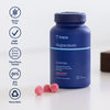 Trace Minerals Magnesium Gummies Watermelon; sininen sylinterinmuotoinen muovipullo, jossa lukee ”trace Magnesium Gummies”, mattapinnalla, on aseteltu valkoiselle tasaiselle pinnalle; lähellä kolme vaaleanpunaista, kuvunmuotoista purukumia; etiketissä selkeää groteskitypografiaa; pullon vieressä pyöreitä kuvakkeita gluteenittomuudesta, cGMP-laitoksesta, kolmannen osapuolen testauksesta, BPA-vapaudesta ja kierrätettävyydestä; ei ihmisiä tai käsiä kuvassa.