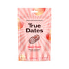 A pink resealable pouch labeled True Dates Sweet Peach features images of sugared peach slices and a date fruit. The packaging highlights include dates with a candy flavour, no added sugar, rich in fiber, and natural flavours. Matte finish on flexible plastic. Upright standing package with product information printed on front in clear sans-serif type. Solid white background, no people or props visible, centered front-facing shot.