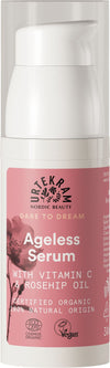 Urtekram Dare to Dream Ageless Seerumi, pullo ikääntymistä vastustavalle seerumille C-vitamiinilla, ruusunmarjaöljyllä ja vegaaneille sopivilla ainesosilla; etiketti korostaa luomusertifikaattia ja 100-prosenttisesti luonnollista alkuperää; pakkaus vaaleanpunainen kukkakuvioin; pullo sylinterimäinen mattapinnalla pumppuannostelijalla; etikettiteksti selkeällä groteskifontilla valkoisena ja hopeisena vaaleanpunaisella pohjalla; ei ihmisiä eikä käsiä näkyvissä, tausta yksinkertainen, tuote keskitettynä.