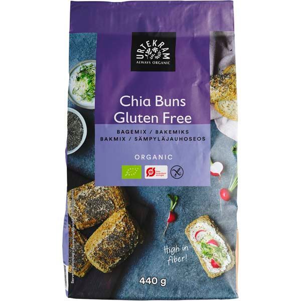 Urtekram Gluteeniton Luomu Chia Leipäjauhoseos; violetti Urtekram-gluteenitonluomu Chia Buns -leivontajauhepussi mattapinnalla, suorakulmainen ja pystyssä seisova; etiketissä valokuvia pyöreistä chia-sämpylöistä tasaisella alustalla, osa koristeltu tuorejuustolla ja retiisiviipaleilla; teksti kertoo runsaasta kuitupitoisuudesta ja 440 gramman painosta selkeällä groteskikirjasimella; tasainen tausta, ei ihmisiä tai käsiä.