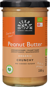 Urtekram Luomu Maapähkinävoi Crunchy; purkki Urtekramin luomu crunchy-maapähkinävoita oranssilla etiketillä, esillä ei lisättyä sokeria ja runsaasti proteiinia; vegaaniystävällinen levite 230 gramman purkissa mustalla kannella; purkki lieriömäinen, kirkasta lasia kiiltäväpinnalla; muovinen kansi mattamusta ja uurteinen; oranssissa paperietiketissä valkoista lihavoitua groteskitekstiä ja mustia yksityiskohtia; tuote yksin valkoisella taustalla studiokuvassa.