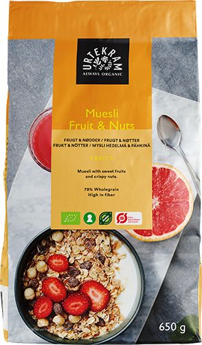 A bag of Urtekram Muesli Fruit & Nuts, 650g, made of matte-finish material. The front shows a bowl filled with muesli containing fruit and nuts, topped with strawberries; a spoon and sliced grapefruit halves are also pictured. Background is plain. Label displays product name in clear sans-serif lettering. No people or hands present. Medium shot focused on the package.