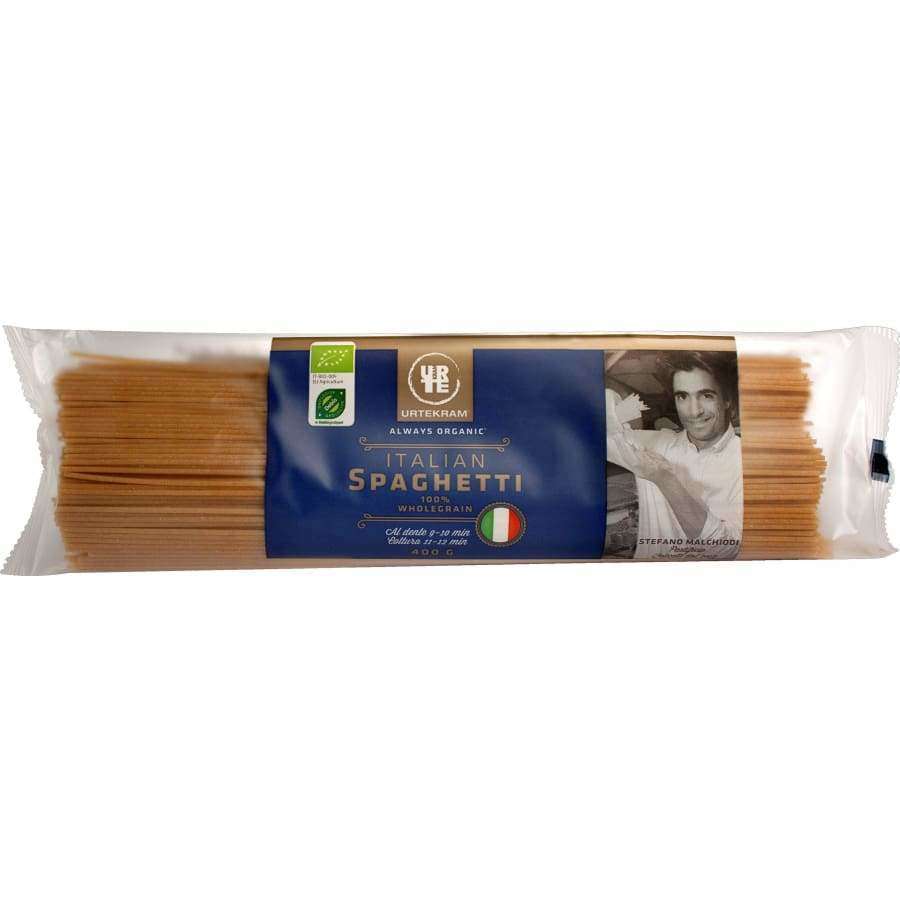 Urtekram Luomu Täysjyväspagetti, pakkaus luomu-italialaiselle täysjyväspagetille sinisellä etiketillä, sertifikaattilogot ja kuva hymyilevästä kokista; Italian lippu näkyy ylpeästi etusivulla; etiketissä sekä groteski- että käsialatyylistä typografiaa; pakkaus suorakulmainen kirkasta muovia mattapintaisin osioin; ei ihmisiä eikä käsiä näkyvissä; tausta yksinkertainen, tuote keskitetty kuvaan.