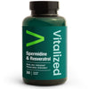 Vitalized Spermidine & Resveratrol; tummanvihreä pullo tekstillä vitalized sisältää Spermidine & Resveratrol -kapseleita, 30 kappaletta, antioksidanttihyötyjä englanniksi ja saksaksi; pullo mattapintainen ja lieriömäinen kierrekannella; etikettitekstissä groteskifontti valkoisena ja kultaisena; tausta valkoinen, ei ihmisiä tai käsiä kuvassa.