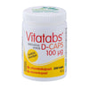 Vitatabs D-Caps 100 mikrog -purkki, 200 kapselia; valkoinen, mattapintainen ja sylinterimäinen muovipullo; keltainen etiketti suomenkielisellä tekstillä; korkki valkoinen, päällä vihreää tekstausvapaata kirjoitusta; tuotenimi ja annostus lihavoiduin mustin kirjaimin; kuvattu yksiväristä taustaa vasten, ei ihmisiä tai muuta ympäristöä näkyvissä.