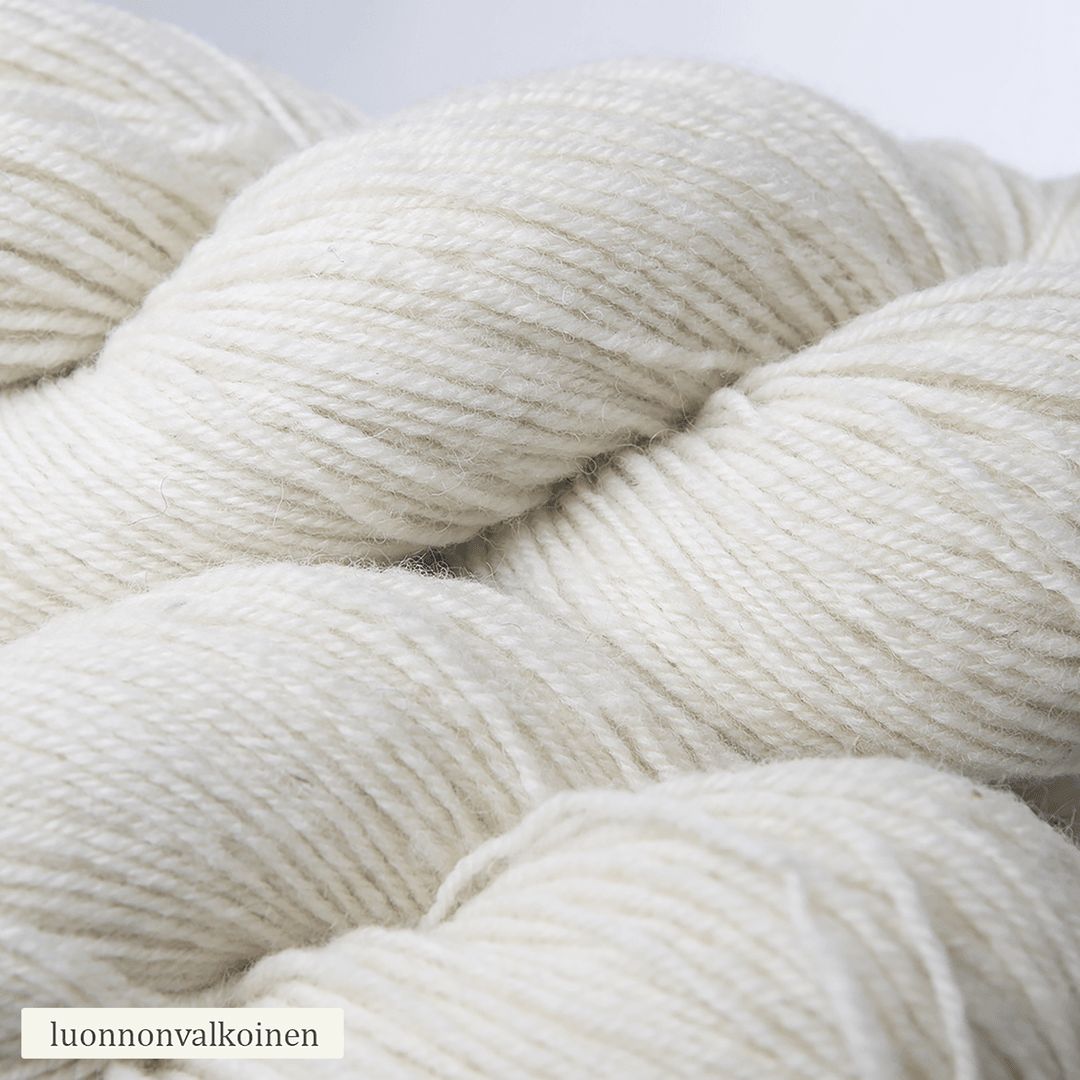 Close-up of several skeins of luonnonvalkoinen yarn, showing the soft texture and subtle fibers. The yarn is off-white and loosely twisted with a matte finish, bundled in oval skeins. No packaging or labels attached to skeins. The word “luonnonvalkoinen” appears in simple font in one corner on a neutral background. No people or hands visible in the shot.