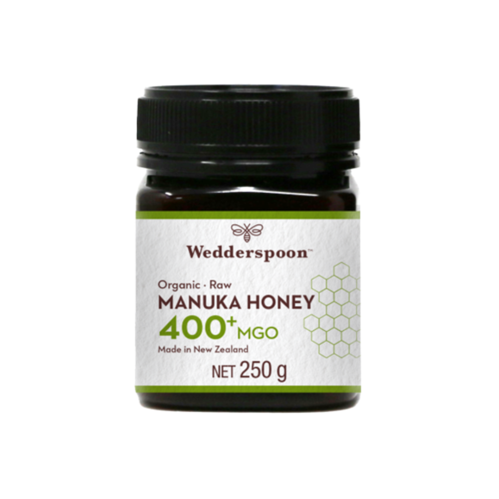 Wedderspoon Luomu Manuka-hunaja 400+ MGO; purkki Wedderspoon Organic Raw Manuka Honey 400+ MGO, 250 g, mustalla muovisella kierrekannella ja valkoisella mattaetiketillä; etiketissä mustaa tekstiä, kuusikulmainen hunajakennokuvio sekä luettavat tiedot Uuden-Seelannin alkuperästä ja luomusertifioinnista; purkki lieriömäinen, kuvattu vaaleaa taustaa vasten.