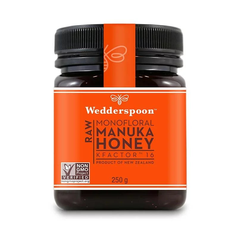 Wedderspoon Manuka-hunaja KF16 -purkki; oranssi etiketti, KFactor 16, Non-GMO Project Verified, 250 g, peräisin Uudesta-Seelannista; purkki kirkasta sylinterimäistä muovia mustalla kierrekannella, pinnan viimeistely kiiltävä; etiketissä valkoista ja mustaa tekstausvapaata tekstiä; tausta yksinkertainen; ei ihmisiä tai muita esineitä näkyvissä; keskikokoinen kuva.