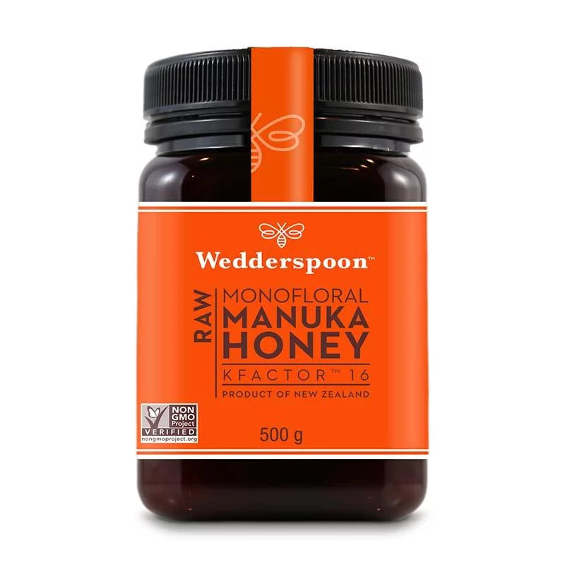 Wedderspoon Manuka-hunaja KF16 -purkki, 500 g; oranssi etiketti tuotetietoineen ja Non-GMO-tarkastusmerkki; muovipurkki sylinterimäinen mattamustalla kierrekannella; luettavassa tekstissä brändinimi ja tuotetyyppi lihavoidulla tekstausvapaalla fontilla; tausta valkoinen, ei ihmisiä tai käsiä näkyvissä.
