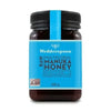 Wedderspoon Manuka-hunaja KFactor 12 -purkki, 500 g; sylinterinmuotoinen mattapintainen purkki mustalla kierrekannella, sininen etiketti tekstillä "Product of New Zealand" ja "non-GMO verified"