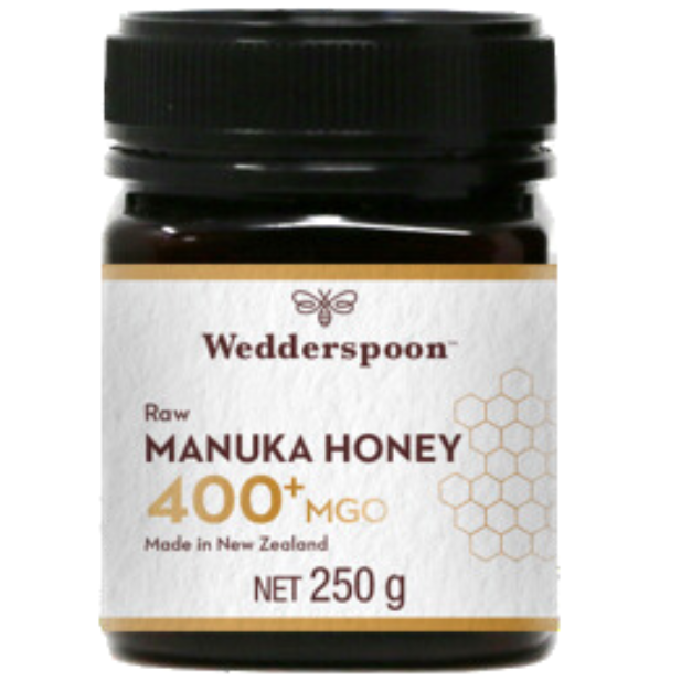 Wedderspoon Manuka-hunaja 400+ MGO; purkki Wedderspoon Raw Manuka Honey 400+ MGO -hunajaa Uudesta-Seelannista, 250 g, mustalla kierrekannella; purkki lieriömäinen, valmistettu tummasta läpinäkymättömästä materiaalista; pääetiketti valkoinen hunajakennokuviolla ja yksinkertaisella groteskitekstillä; keskeiset tuotetiedot kuten Wedderspoon ja 400+ MGO näkyvissä; ei ihmisiä tai käsiä kuvassa; vaalea tausta, tavanomainen tuotekuvakulma.