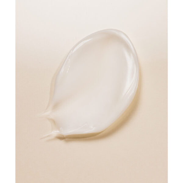 Whamisa Organic Flowers Eye Essence; lähikuva läpikuultavasta, geelimäisestä kosteusvoiteesta soikean muotoisena läikkänä vaalealla beigellä pinnalla; ei näkyvää pakkausta, etikettitekstiä tai brändäystä; kosteusvoiteen pinta kiiltävä lievällä heijastuksella; kuvassa ei ihmisiä, käsiä tai toimintaa; tausta tasainen ja yksivärinen.