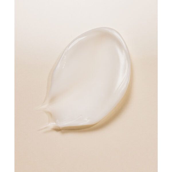 Whamisa Organic Flowers Eye Essence; lähikuva läpikuultavasta, geelimäisestä kosteusvoiteesta soikean muotoisena läikkänä vaalealla beigellä pinnalla; ei näkyvää pakkausta, etikettitekstiä tai brändäystä; kosteusvoiteen pinta kiiltävä lievällä heijastuksella; kuvassa ei ihmisiä, käsiä tai toimintaa; tausta tasainen ja yksivärinen.