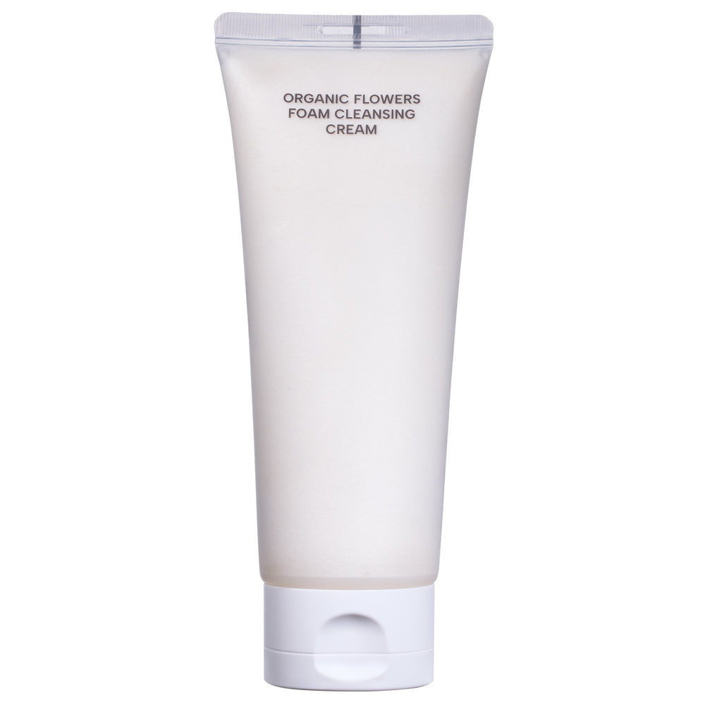 Whamisa Organic Flowers Foam Cleansing Cream; valkoinen mattapintainen tuubi tekstillä ”Organic Flowers Foam Cleansing Cream” seisoo pystyssä tasaisella taustalla; pakkaus pehmeä lieriö pyöristetyllä korkilla; etikettiteksti selkeällä groteskifontilla; ei ihmisiä tai muita esineitä kuvassa; tuubi tuo mieleen luonnonmukaisen ihonhoidon tasaista taustaa vasten.