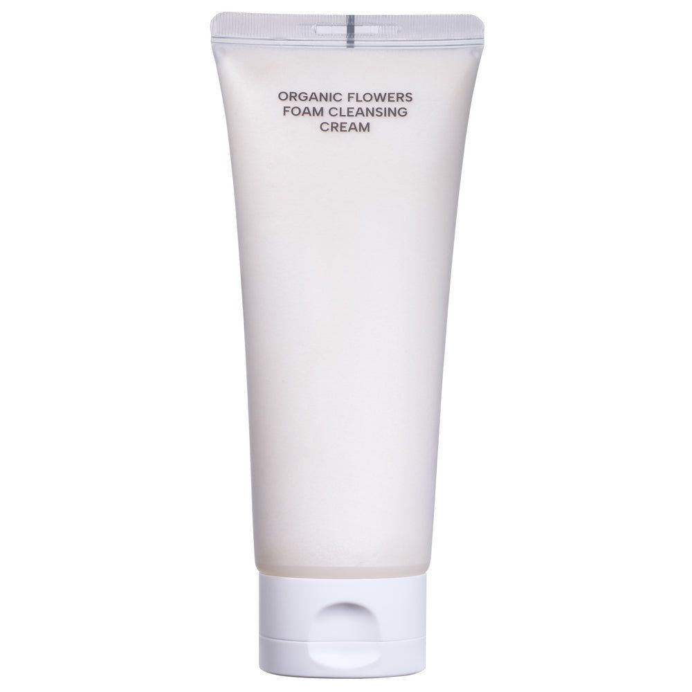 Whamisa Organic Flowers Foam Cleansing Cream; valkoinen mattapintainen tuubi tekstillä ”Organic Flowers Foam Cleansing Cream” seisoo pystyssä tasaisella taustalla; pakkaus pehmeä lieriö pyöristetyllä korkilla; etikettiteksti selkeällä groteskifontilla; ei ihmisiä tai muita esineitä kuvassa; tuubi tuo mieleen luonnonmukaisen ihonhoidon tasaista taustaa vasten.