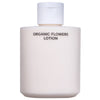 Whamisa Organic Flowers Lotion Double Rich; valkoinen pullo tekstillä ”ORGANIC FLOWERS LOTION” ja valkoisella läppäkorkilla, kuvattu tasaisella taustalla korostaen luonnonmukaisia ainesosia; pullo sileä ja mattapintainen, muoto lieriömäinen; etiketissä yksinkertaista mustaa versaaligroteskia; ei muita esineitä, ihmisiä tai toimintaa kuvassa.