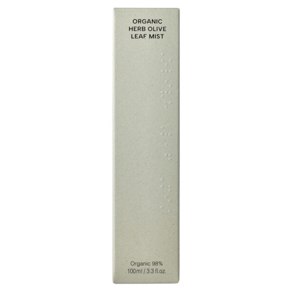Whamisa Organic Flowers Olive Leaf Mist; beige suorakaiteen muotoinen rasia tekstillä ”Organic Herb Olive Leaf Mist”, merkinnät 98 % luonnonmukaista ja ”100ml / 3.3 fl. oz.”; pakkauksen etusivulla pistekirjoitusta esteettömyyden vuoksi; pinta mattapintainen, groteskityyppografiaa mustalla ja vihreällä musteella; rasia kuvattu pystyasennossa tasaisella valkoisella taustalla, ei ihmisiä tai käsiä.