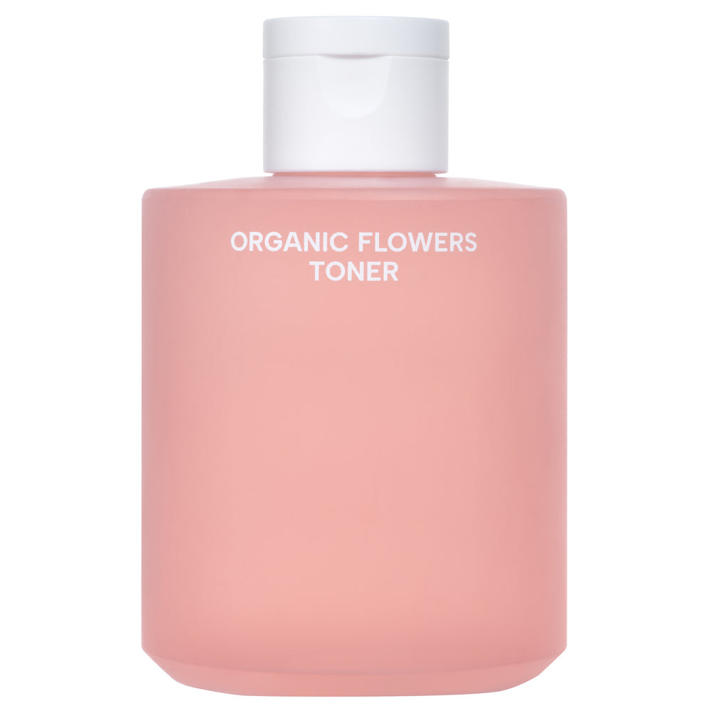 Whamisa Organic Flowers Toner Deep Rich; vaaleanpunainen pullo tekstillä ”ORGANIC FLOWERS TONER” valkoisella korkilla, rikastettu kasviuutteilla, tasaisella valkoisella taustalla; pullo lieriömäinen ja läpikuultamatonta materiaalia mattapinnalla; etiketti versaaligroteskitekstillä; ei ihmisiä tai käsiä; lähikuva tuotteesta.