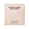 Whamisa Organic Flowers Water Cream; beige suorakaiteen muotoinen mattapintainen rasia; etusivulla teksti ”ORGANIC FLOWERS WATER CREAM”, ”Organic 95%” ja ”50ml / 1.6 fl. oz.” selkeällä groteskikirjasimella; pinnassa tasainen kohokuvioitujen pisteiden kuvio; ei ihmisiä tai muita esineitä, tuote kuvattu tasaisella taustalla.