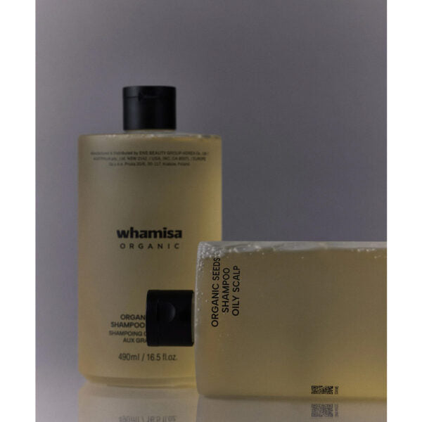 Whamisa Organic Seeds Shampoo Oily Scalp; kaksi Whamisa Organic -shampoopulloa, toinen pystyssä ja toinen kyljellään, tasaista taustaa vasten; pullot lieriömäisiä pumppuannostelijoin, valmistettu mattapintaisesta materiaalista; etiketeissä tuotenimi ja tiedot mustalla groteskitekstillä, mainiten luonnonmukaisia ainesosia; ei ihmisiä tai muita esineitä näkyvissä.