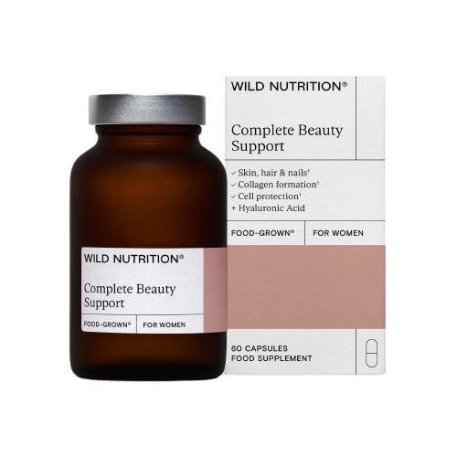 Wild Nutrition Complete Beauty Support, ruskea lasipullo pakkauksensa vieressä, joka korostaa hyötyjä iholle, hiuksille, kynsille, kollageenin muodostukselle, solunsuojaukselle ja hyaluronihapolle; ravintolisä sisältää 60 kapselia; pullo pinnaltaan sileä ja puolikiiltävä, valkoinen kierrekorkki; typografia selkeä ja moderni; molemmat esineet pystyssä valkoisella taustalla studiokuvassa.