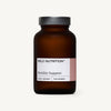 Wild Nutrition Fertility Support -pullo, ruskea lasipullo mattametallisella kannella, sylinterimäinen muoto ja valkoinen suorakulmainen etiketti, keskitettynä sileälle vaalealle taustalle; etiketissä lukee "Wild Nutrition Fertility Support, Food-Grown" ja "For Women" tekstausvapaalla fontilla; ei ihmisiä tai käsiä näkyvissä; suora edestäpäin otettu tuotekuva.
