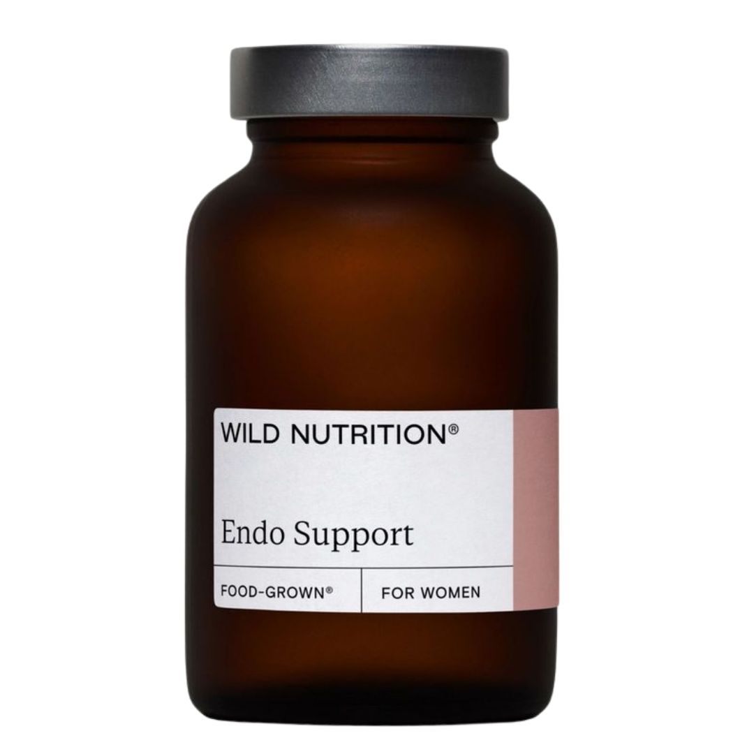 Wild Nutrition Endo Support; ruskea lasipullo tekstillä Wild Nutrition Endo Support, vaaleanpunainen ja valkoinen Food-Grown-etiketti naisille, kuvattu valkoista taustaa vasten; pullo sylinterin muotoinen kierrekorkilla ja mattapinnalla; etikettikirjasin lihavoitua groteskia tuotenimessä; ei ihmisiä, käsiä tai rekvisiittaa kuvassa, suoraviivainen tuotekuva.