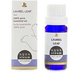 Aqua Oleum Eteerinen Laakerinlehtiöljy; sininen lasipullo tekstillä "Laurel Leaf aqua oleum essential oil" yhteensopivan pakkauksen vieressä, jossa kultalehtikuvio ja yksityiskohtaiset tuotetiedot eteerisestä öljystä; pullo sylinterinmuotoinen mustalla korkilla, etiketti mattapintainen groteskitekstillä; laatikko suorakulmainen valkoinen näkyvin kultafoliokuvioin ja tummalla painetulla tekstillä; molemmat vaalealla taustalla, ei ihmisiä tai käsiä kuvassa.