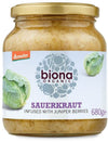 Biona Organic Hapankaali, luonnollisesti käytetty ja maustettu katajanmarjoilla; lieriömäinen, kirkas lasipurkki kultaisella metallisella kierrekannella; etiketti mattapaperia, kaalikuvituksia ja mustaa groteskitekstiä eri kokoina vaalealla pohjalla; luettavissa tuotenimi, ainesosat ja paino 680 grammaa; vaalea studiotausta, ei ihmisiä tai käsiä.