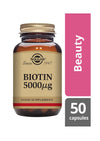 Solgar Biotin 5000 µg -ravintolisäpullo, sanan Beauty vierellä ja merkintä 50 kapselia oikeassa alakulmassa, korostaen hyödyt terveille hiuksille, iholle ja kynsille; pullo ruskeaa lasia kultaisella metallisella korkilla ja mattaviimeisteltyllä etiketillä serif-tekstillä mustana ja kultaisena; tuote kuvattu valkoista taustaa vasten; ei ihmisiä tai käsiä näkyvissä.