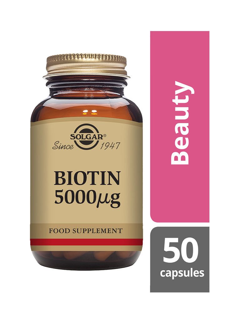Solgar Biotin 5000 µg -ravintolisäpullo, sanan Beauty vierellä ja merkintä 50 kapselia oikeassa alakulmassa, korostaen hyödyt terveille hiuksille, iholle ja kynsille; pullo ruskeaa lasia kultaisella metallisella korkilla ja mattaviimeisteltyllä etiketillä serif-tekstillä mustana ja kultaisena; tuote kuvattu valkoista taustaa vasten; ei ihmisiä tai käsiä näkyvissä.