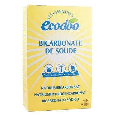 Ecodoo Ruokasooda Puhdistusaineeksi; keltainen suorakulmainen laatikko tekstillä "Ecodoo" suurin sinisin kirjaimin yläosassa, pienempi sininen ranskankielinen teksti listaa käyttökohteita astioille, pyykille ja siivoukseen; lisää kemikaalinimiä painettu pakkaukseen usealla kielellä; pinta vaikuttaa mattaiselta; ei ihmisiä tai käsiä kuvassa, neutraali tausta, selkeä suora edestäpäin otettu kuva.