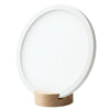 A round, white, flat disc with a thick border stands upright in a small, light wood base on a plain white background. The disc has a matte finish and no visible markings or text. The thin wooden base is rectangular with smooth edges. Background and setting are featureless; there are no visible packaging, people, hands, or actions.