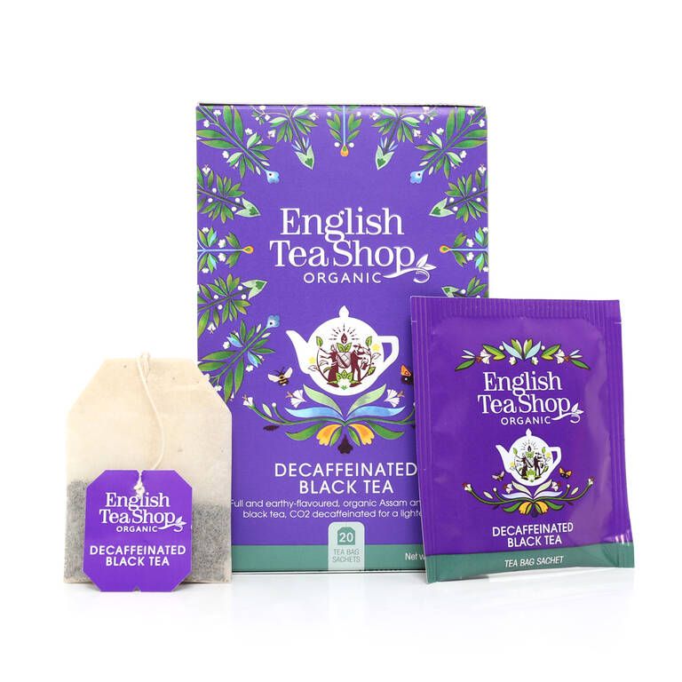 English Tea Shop Luomu Kofeiiniton Musta tee; pakkaus, teepussipussi ja yksittäinen teepussi, kaikki violetin ja valkoisen sävyisiä teekannukuvituksin ja vihrein lehdin, pinta mattapintainen; pääteksti valkoisin versaalikirjaimin antiikvakirjasimella, pienempi teksti keskitettynä; ei ihmisiä tai käsiä, valkoinen studiotausta.