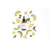 Evolve True Balance Tasapainottava Kasvovoide; ruskea suihkepullo muovisella liipaisimella, puolimatta pinta, ei näkyvää etikettiä tai brändimerkintää, lieriömäinen muoto; ympärillä siististi aseteltuja avokadoviipaleita, inkiväärinpaloja kuorineen ja hedelmälihoineen, litteitä vihreitä lehtiä ja pieniä vihreitä yrttioksia; kaikki aseteltu vaalealle taustalle ylhäältä kuvatussa otoksessa; ei ihmisiä tai käsiä.